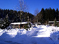 Winterstimmung an einem frühen Nachmittag. Vorne links Holzhäuschen 1, im Hintergrund Hausnummer 6 und rechts das Haupthaus – dort wohnen die Wenigs.